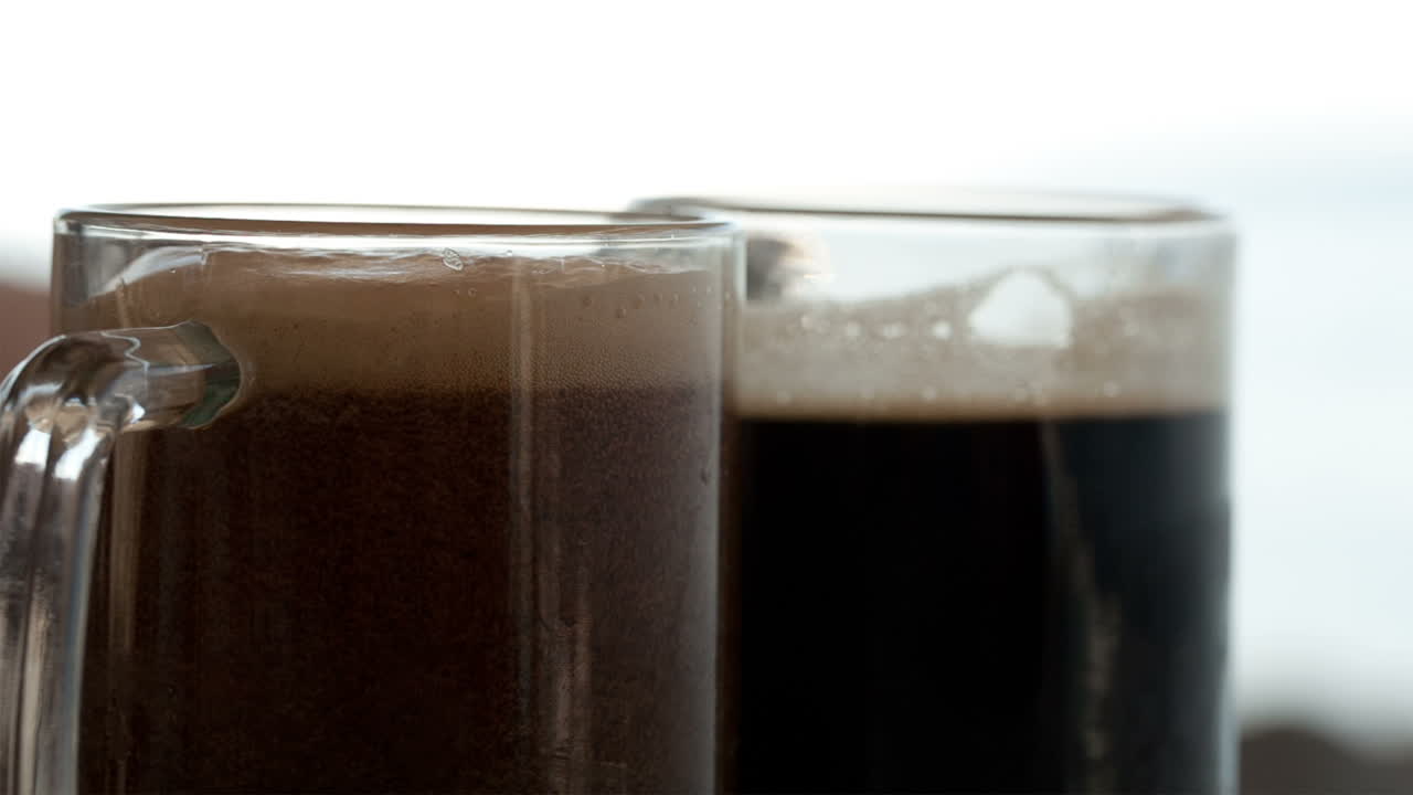 Pouring black beer into the beer cup