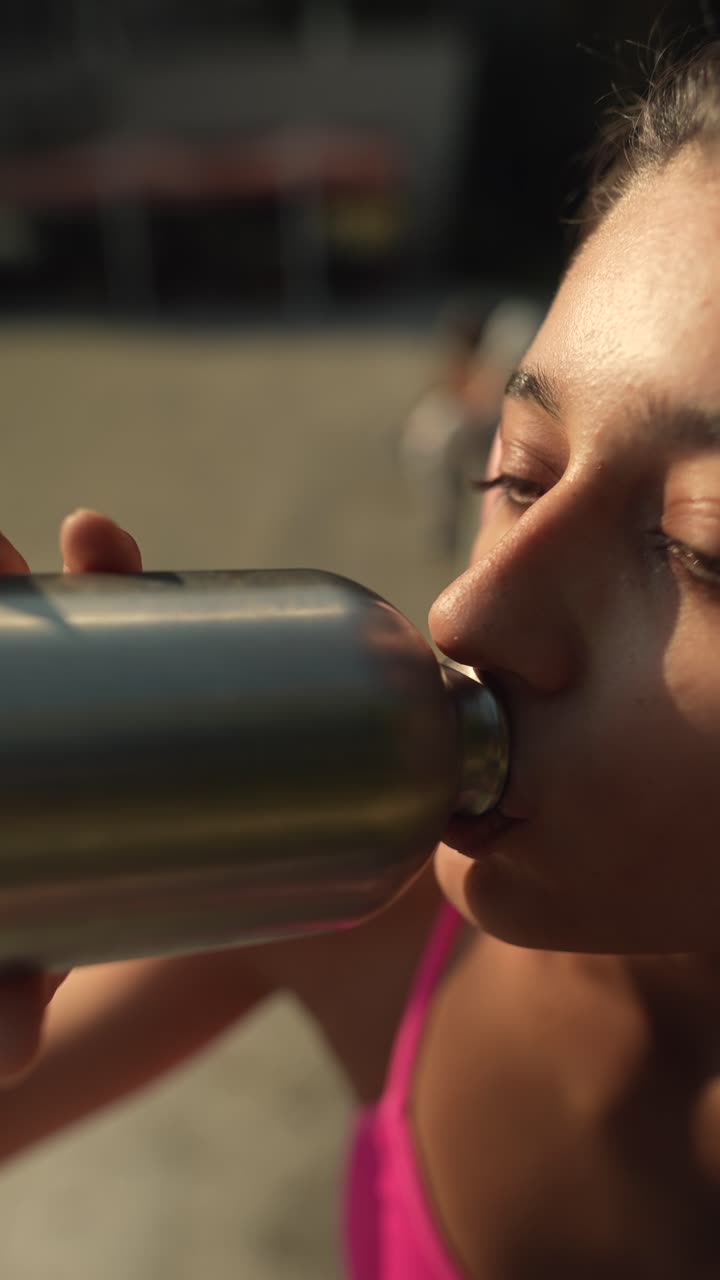 mujer joven bebiendo agua mientras hace ejercicio