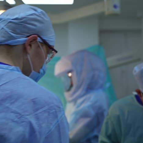 teamwork of doctors. medical workers in blue protective suits conduct an operation in surgical room. operating theater.