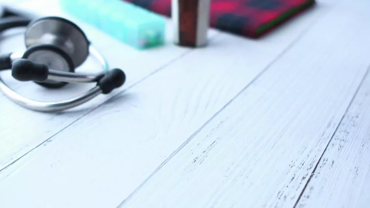 Medico che tiene in mano un blister di pillole con uno stetoscopio sullo sfondo
