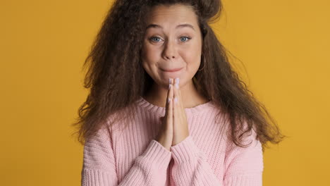 caucasian curly haired woman making a wish to the camera.