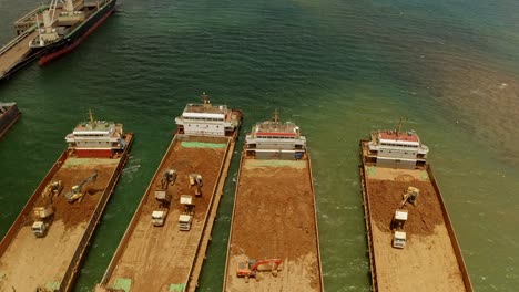 Una-Toma-Aérea-De-Un-Dron-Que-Muestra-Camiones-Cargando-Material-De-Las-Minas-De-Níquel-Taginito-En-Grandes-Barcazas.