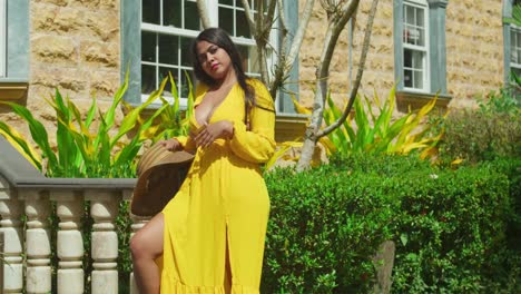 A young woman in a vibrant yellow flowing dress standing in front of a breathtaking castle.