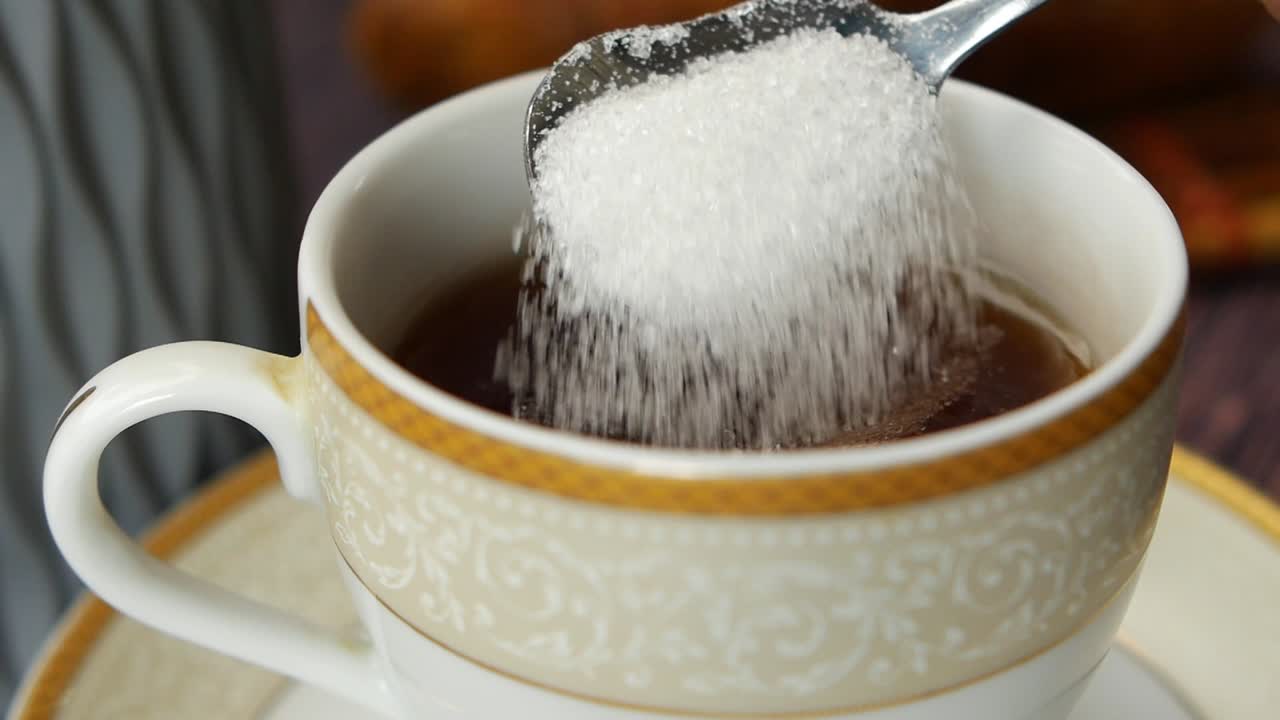 movimiento lento de verter azúcar blanca en una taza de café , vista de arriba ,