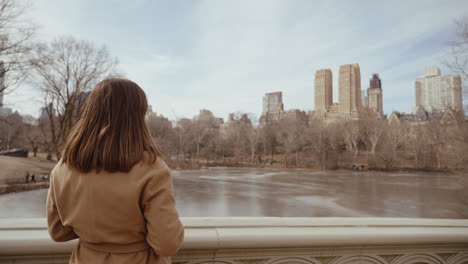 woman taking photos in central park, new york city during winter