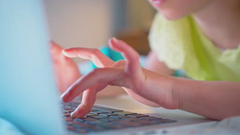 close up of girl in bedroom lying on bed using laptop to do homework