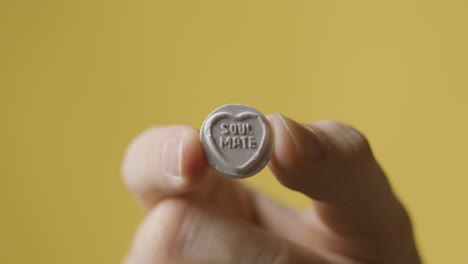 close up of hand holding heart candy avec âme sœur message sur fond jaune