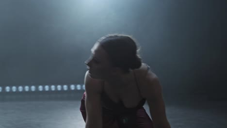 graceful female dancing in studio with smoke and spotlight. silhouette of woman