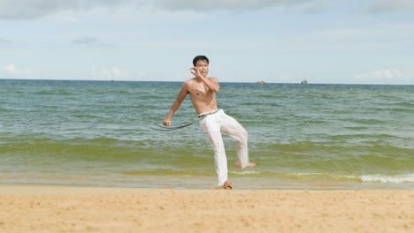 un tipo bailando capoeira en la playa.