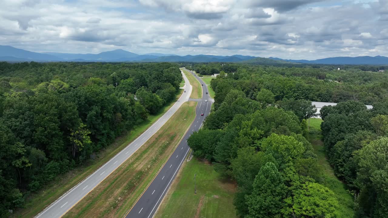 Traffic on Americans highway surrounded by green forest trees and woodland on cloudy Summe day. Aerial panorama wide shot. Blue ridge mountains in Virginia