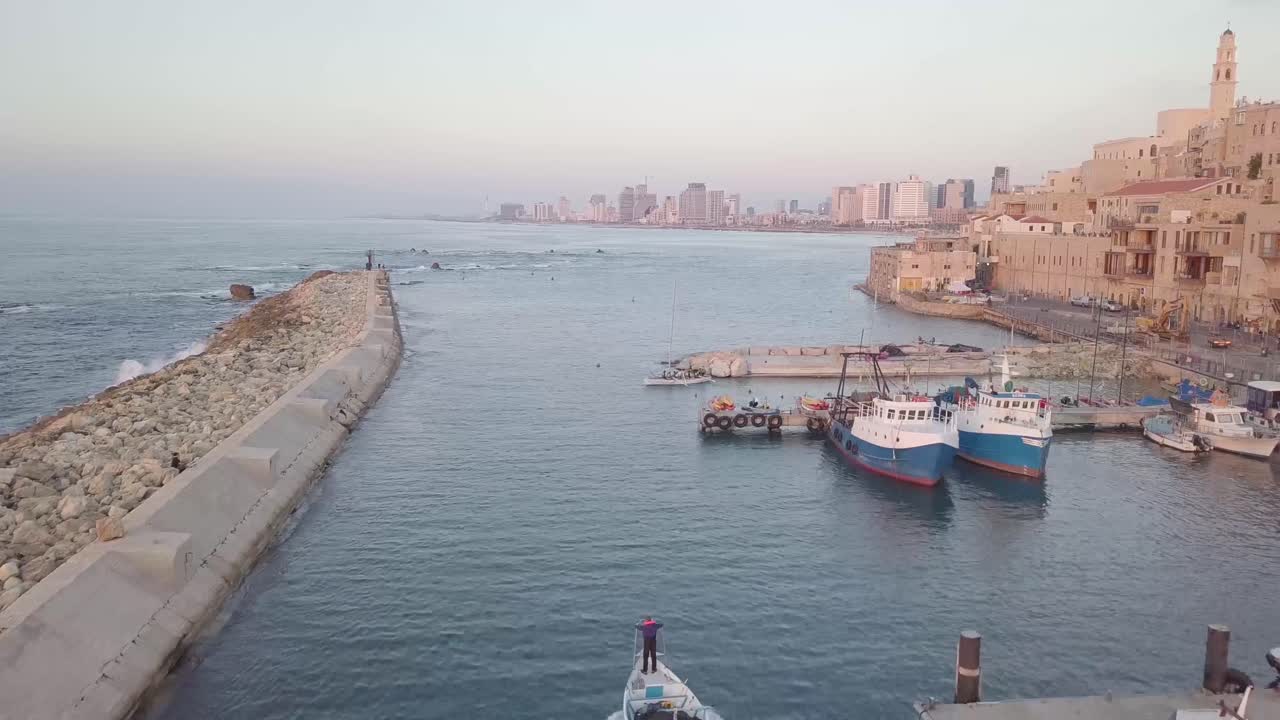 puerto de jaffa con barcos en movimiento que muestran arquitectura de mampostería e influencia medieval mientras que en la distancia está el horizonte moderno de tel aviv alrededor de marzo de 2019