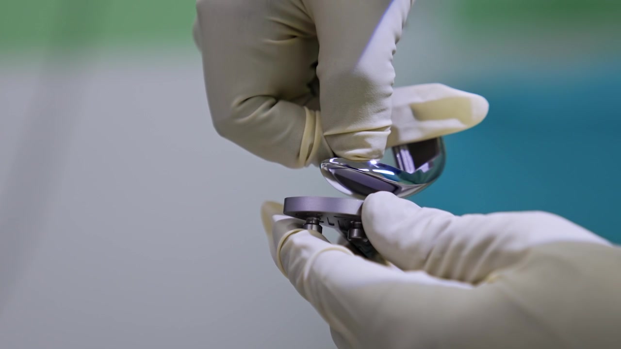Doctor's hands in latex gloves hold a knee joint prosthesis. Orthopedics and trauma surgery. Close up.