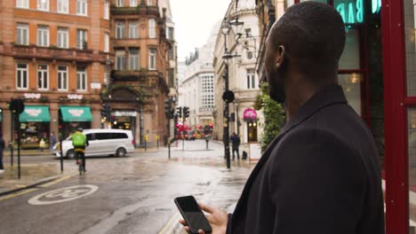 Macho-Negro-Usando-Un-Teléfono-Inteligente-En-Una-Calle-Muy-Transitada-En-Londres