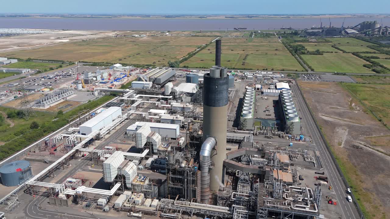 Aerial drone view of industrial power plant with smoke stacks, turbines, and cooling fans generating electricity from gas, coal, and oil in Immingham UK
