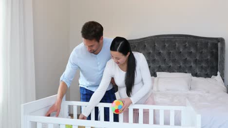Schwangeres-Paar-Legt-Spielzeug-Auf-Babybett-Im-Schlafzimmer-4K