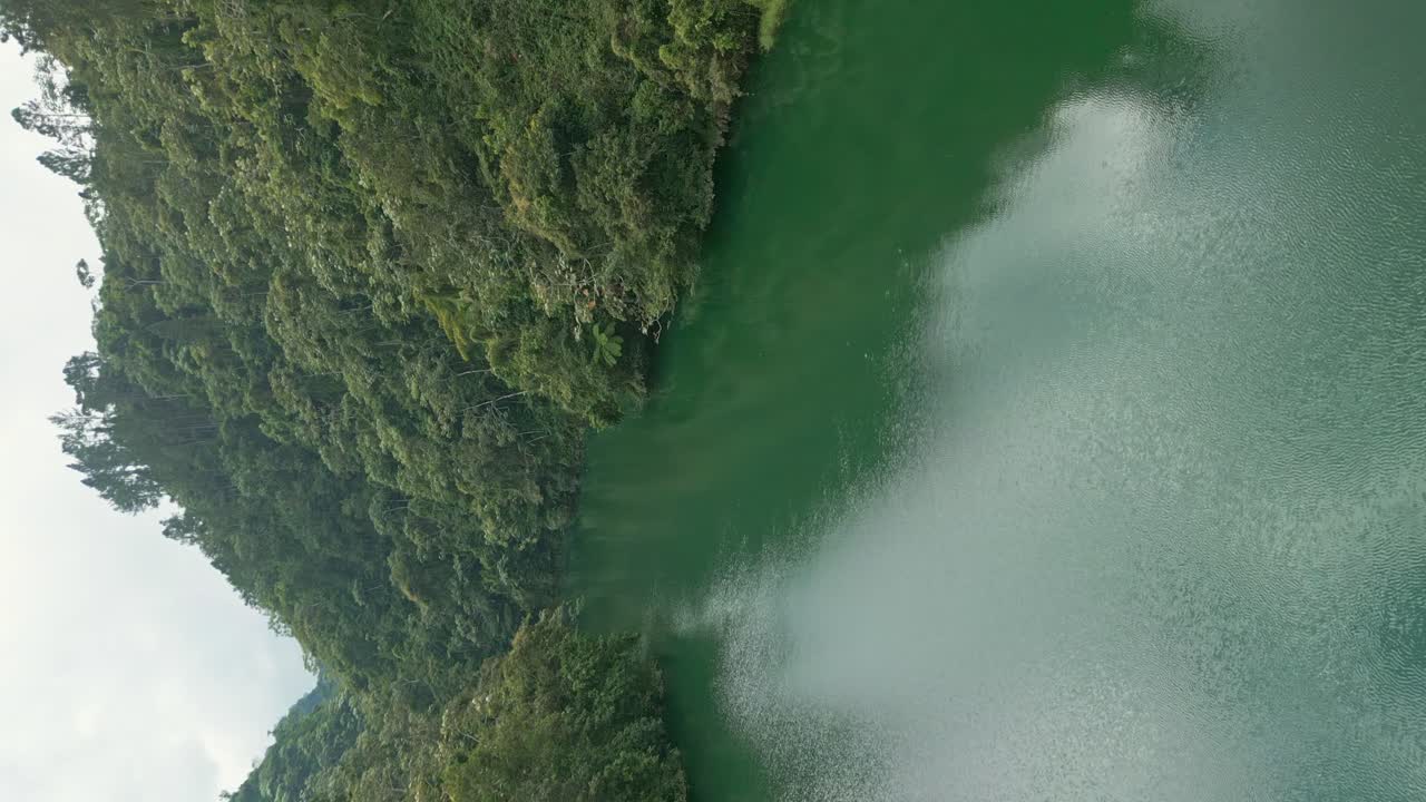 vuelo vertical sobre la presa de tireo con agua verde del río y paisaje de selva tropical en bonao