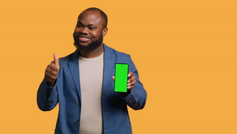 person presenting mockup device, giving thumbs up sign, studio background