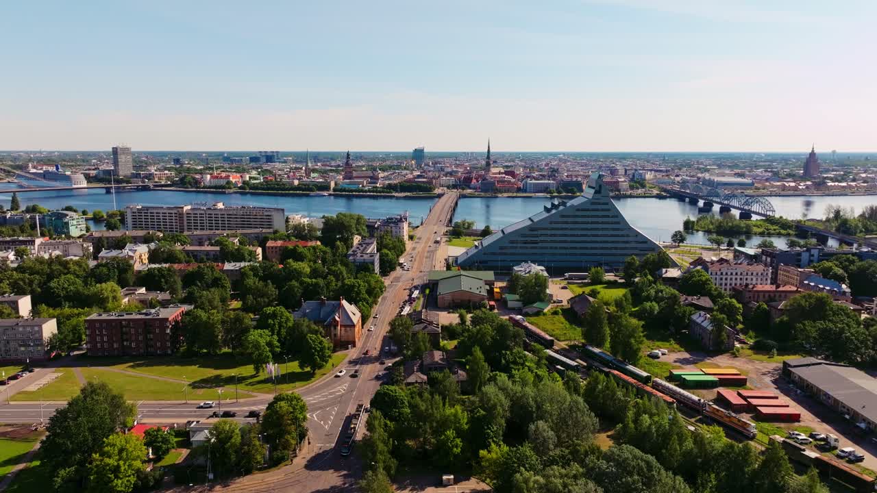 Backward aerial reveals Riga skyline as drone lifts above Victory Park in summer