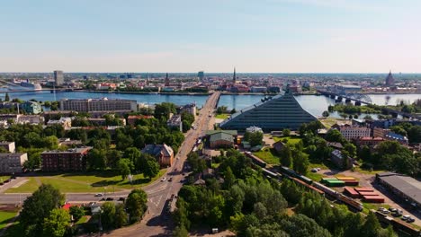 backward aerial reveals riga skyline as drone lifts above victory park in summer