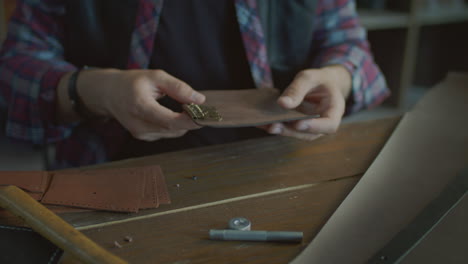 craftsman making leather keychain in home workshop. leather workshop