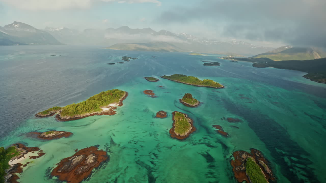 Aerial drone shot over the island of Senja in the Lofoten Ilsands, Norway. High view of the vibrant turquoise sea and the small islands. Breathtaking landscape, untouched natural wonder.