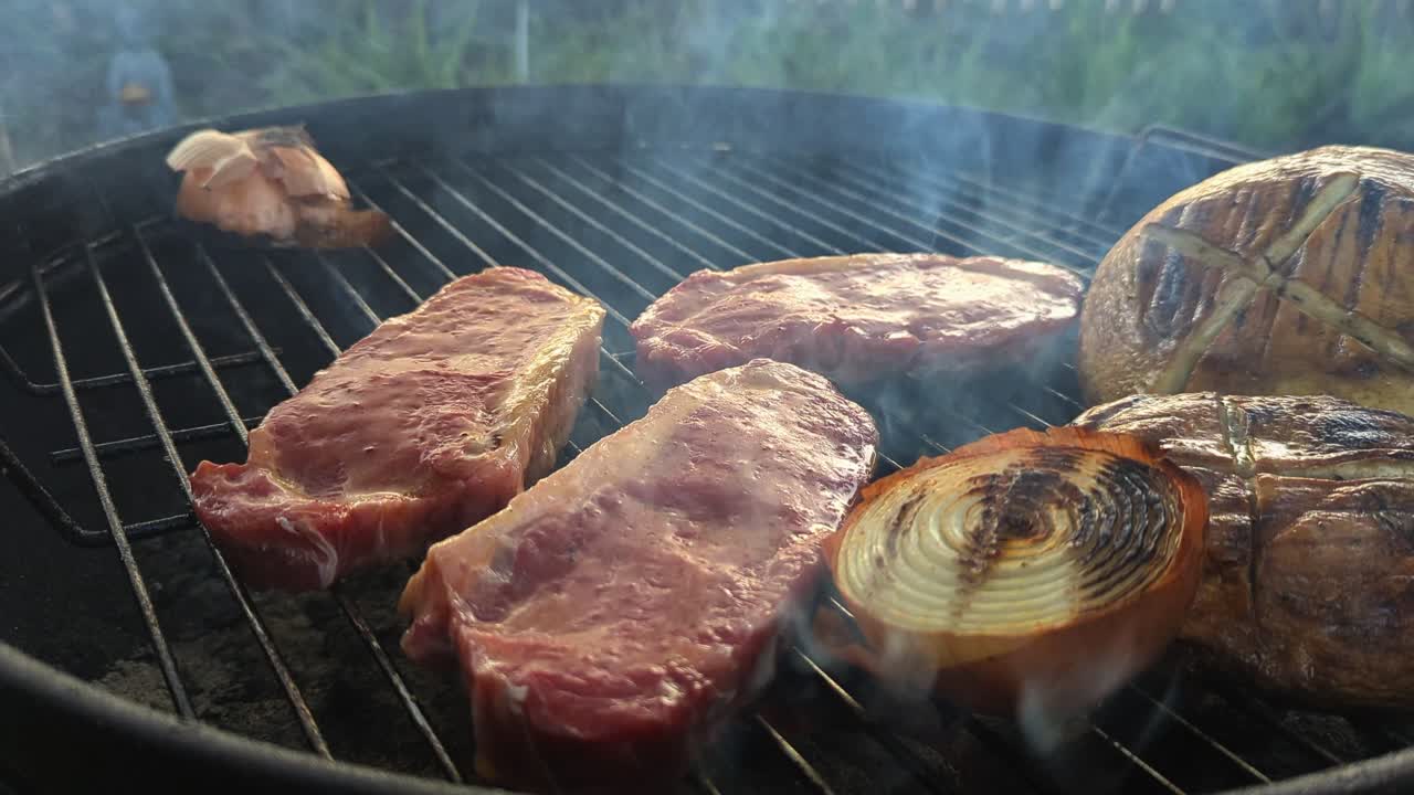 Smokey BBQ with steaks and mushrooms grilling over the hot coals.