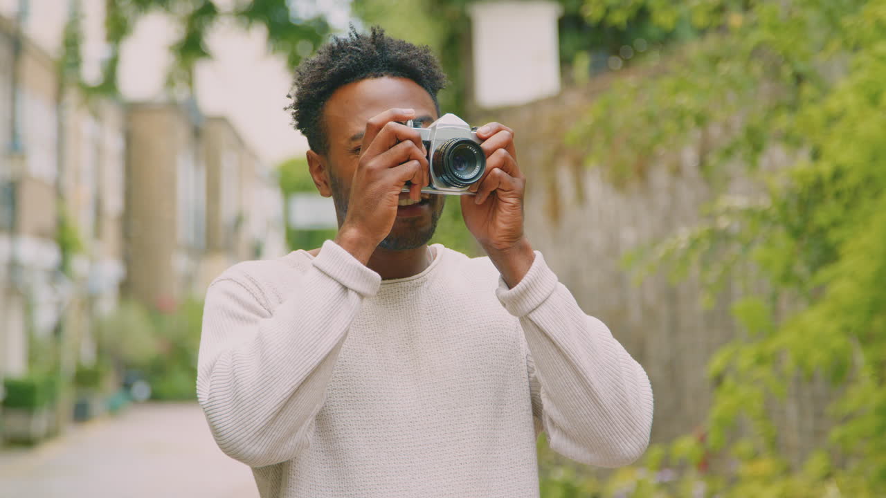 Young Man In City Taking Photo On Digital Camera To Post To Social Media