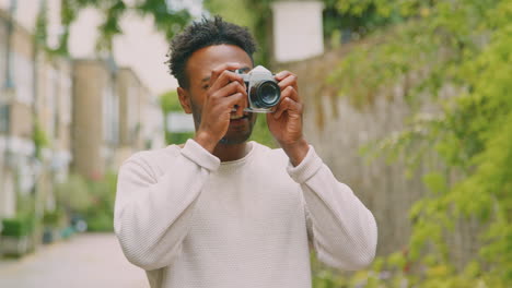 young man in city taking photo on digital camera to post to social media