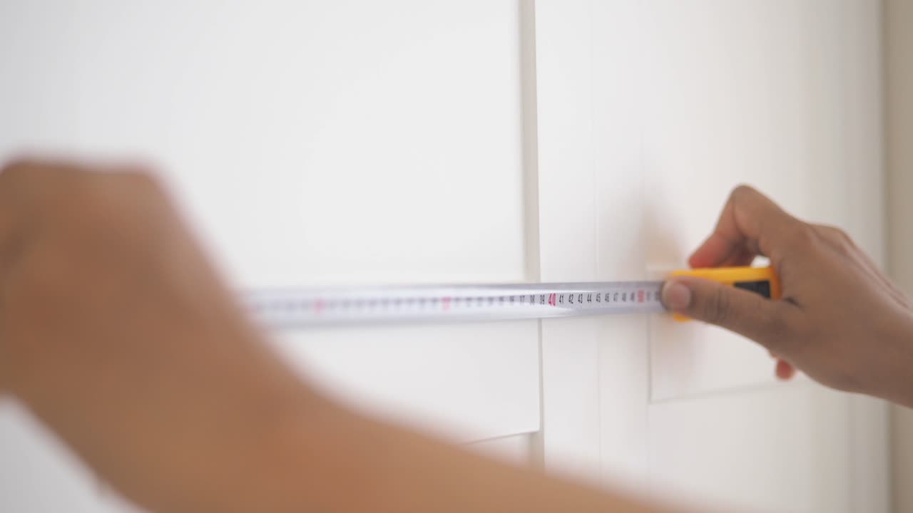 Measuring a cabinet with a tape measure