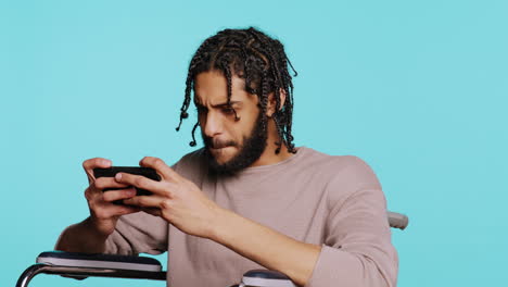 man in wheelchair feeling sad after losing videogame, playing on mobile phone