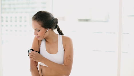 Mujer-Joven-En-Forma-Escuchando-Un-Dispositivo-De-Música-En-Un-Brazalete-Y-Cambiando-De-Canción.