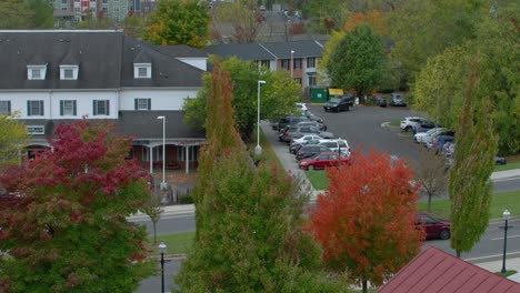 tilt up shot of cars driving by scenic suburban neighborhood with modern multi-story apartment building on cloudy autumn day, blacksburg virginia