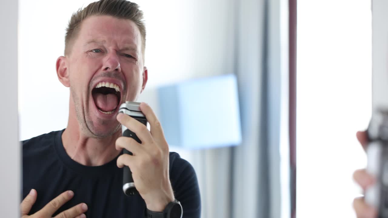 Mand laver overdrevne ansigtsudtryk, mens han barberer sig med en elektrisk barbermaskine