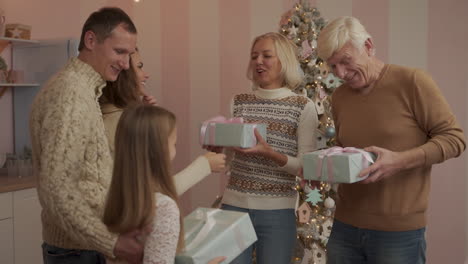 parents, grandparents and granddaughter exchanging christmas presents