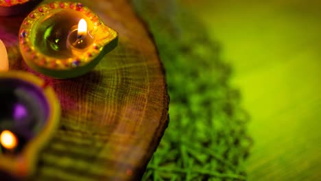 video of glowing lit diwali candles in circle on wooden and green surface