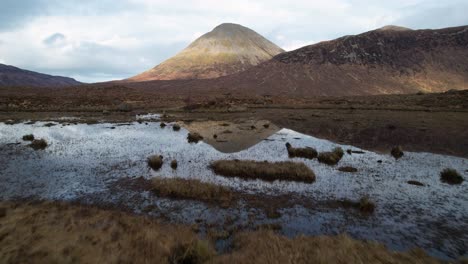 fast drone dolley shot over autumn colored with the high cuillin mountains in the background at isle of skye