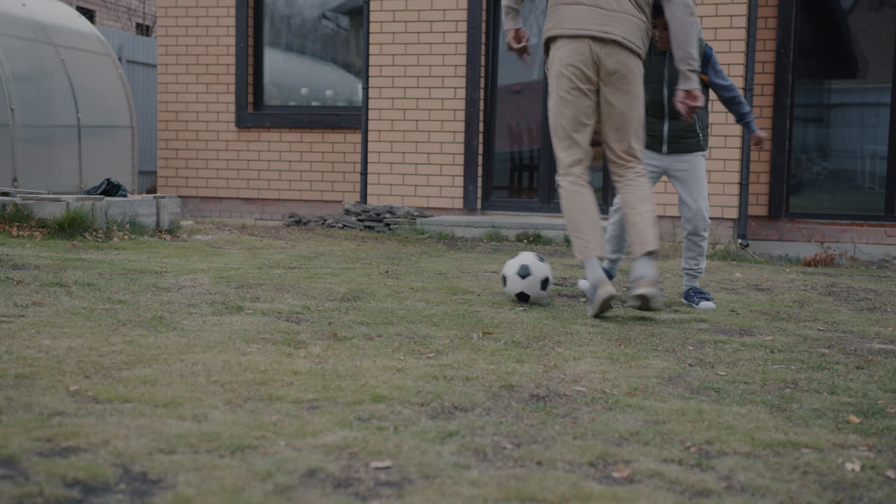 padre e hijo jugando al fútbol en el patio trasero
