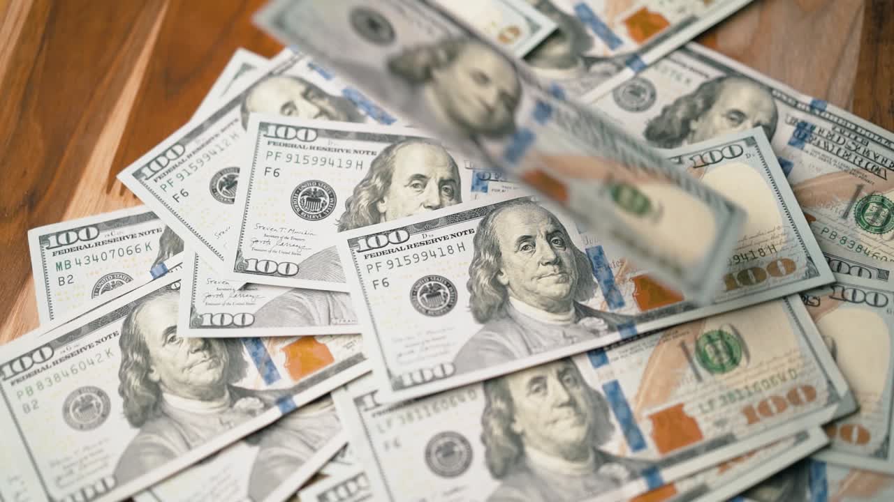 Pila di banconote da 100 dollari che cadono una sull'altra al rallentatore
