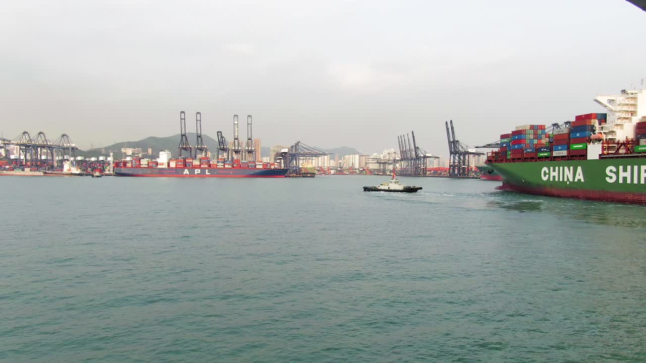 Aerial view of Hong Kong Port, passing under Stonecutters bridge with a Tug boat operation and general view of the city Port.