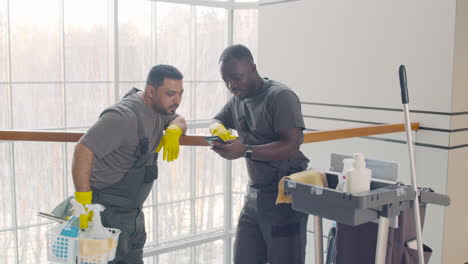 and arabic cleaning men looking at smartphone near a cart cleaning