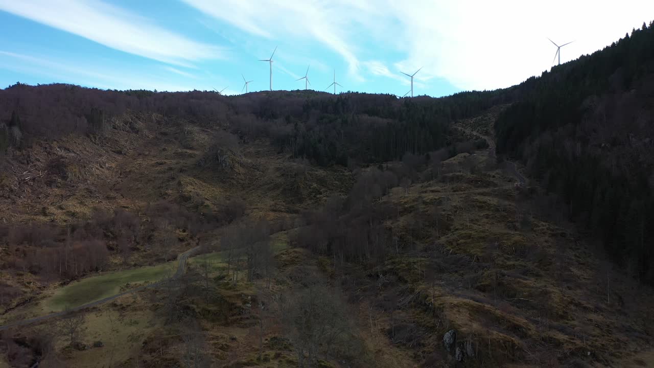 turbinas eólicas girando en la cima de una colina a lo largo de la costa noruega con fondo de cielo azul - antena ascendente que muestra el parque eólico midtfjellet contra un fondo contrastante brillante