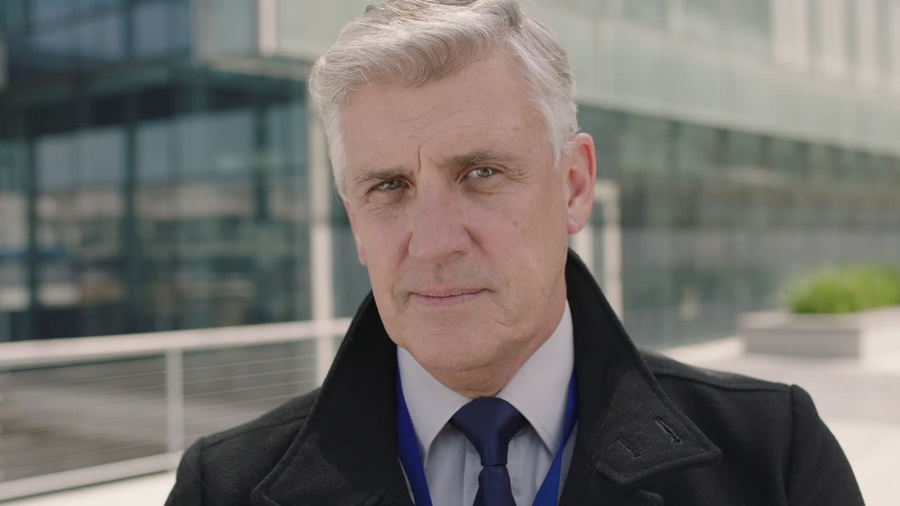 성공한 성숙한 ceo 사업가의 근접 초상화 웃는 자신감 도시 베이크그라운드에서 코트를 입고 눈 이는