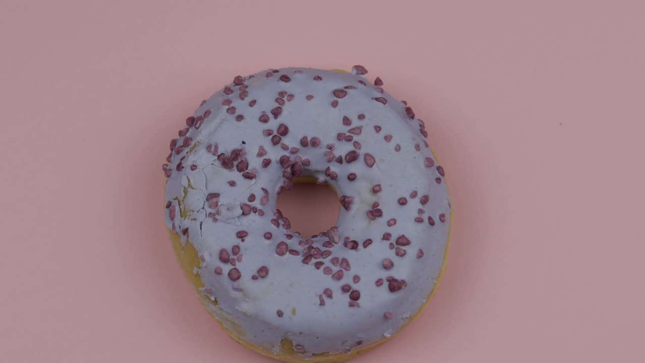 donut dulce girando sobre un fondo rosado. vista superior. donut sabroso y fresco rociado