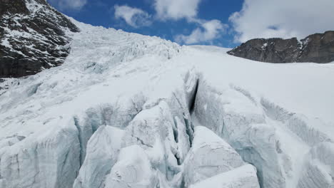 drone close up view of the cracks of a large glacier on a sunny day in winter in the alps