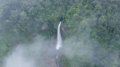 An awe-inspiring aerial shot of Catarata del Toro in Costa Rica, capturing a direct view of the powerful waterfall as it cascades into a deep, circular pool below