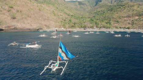 colorful crab claw sail on white wooden jukung outrigger boat near shore of bali