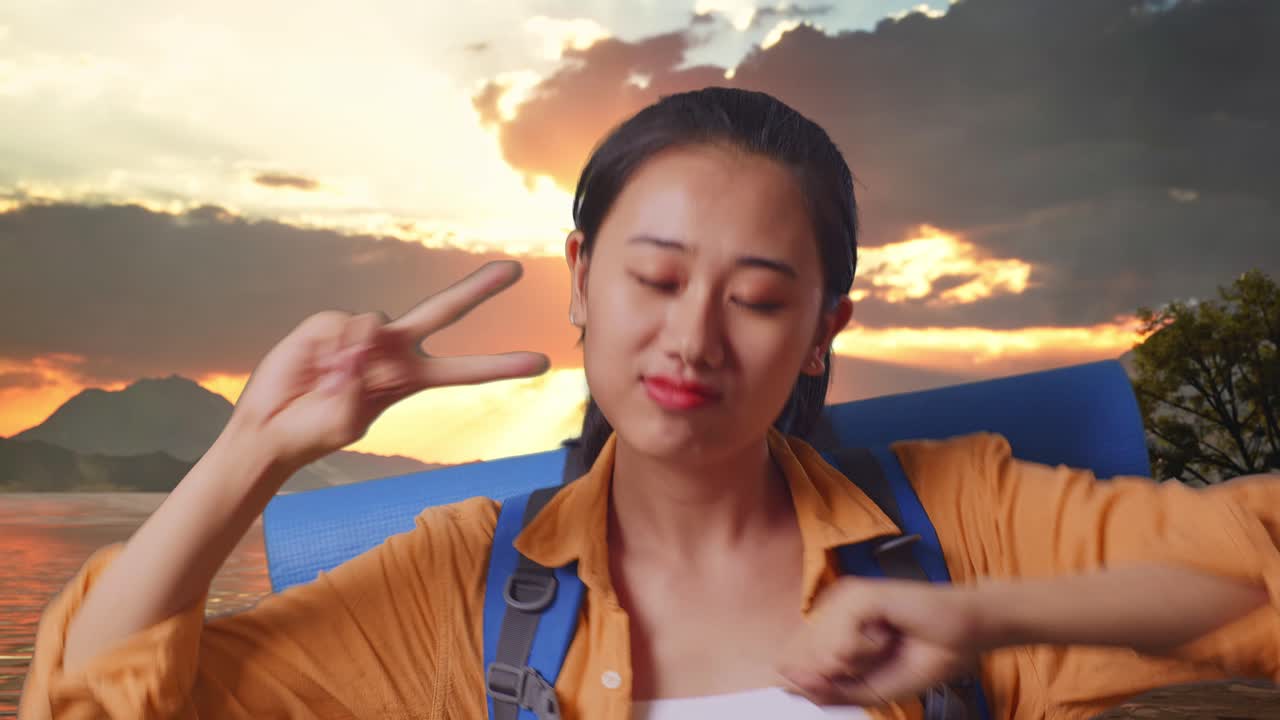 Close Up Of Asian Female Hiker With Mountaineering Backpack Enjoy Dancing At A Lake During Sunset Time