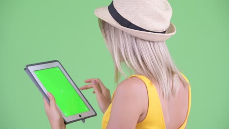 fotografía de estudio de una joven turista vista lateral trasera del uso de una tableta digital con clave de croma espacio de copia contra fondo verde