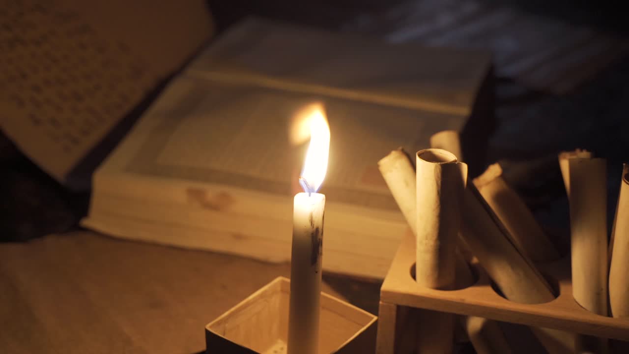 leer un libro bajo una vela encendida en la edad media.