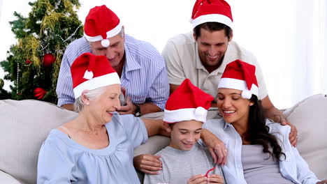 familia viendo a un niño abrir un regalo de navidad